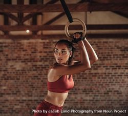 Determined woman exercising with gymnastic rings in gym 5llQM5