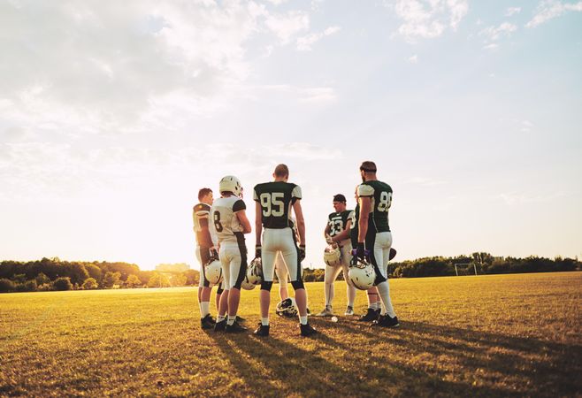 A football team discussing the game at sunset