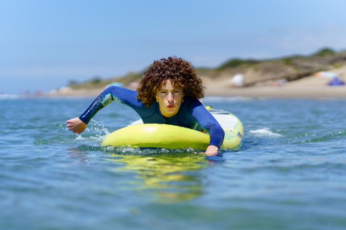 Focused woman on paddleboard rowing with hands in sea