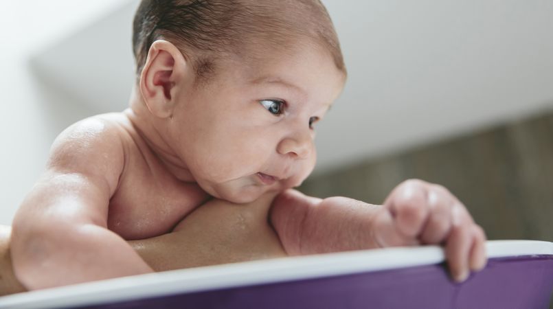 Newborn in the bathtub held by her mother