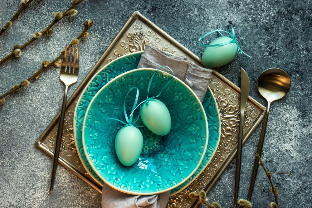 Top view of Easter holiday table setting with teal bowl and teal decorative eggs
