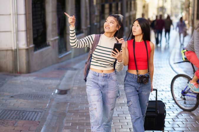 Two women sightseeing and pointing along Spanish street