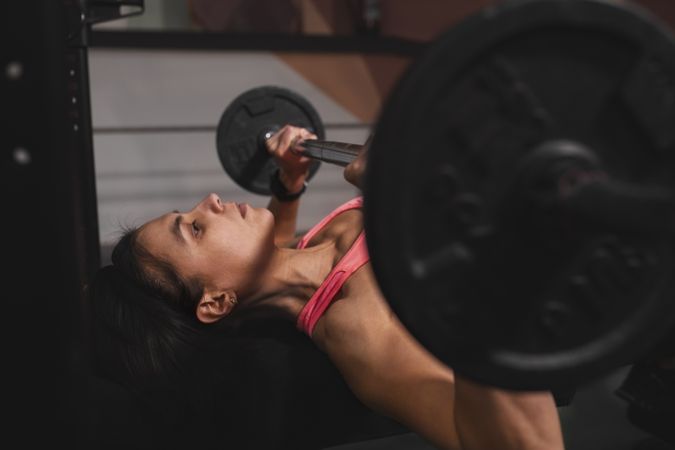 Athletic woman training with barbells in gym