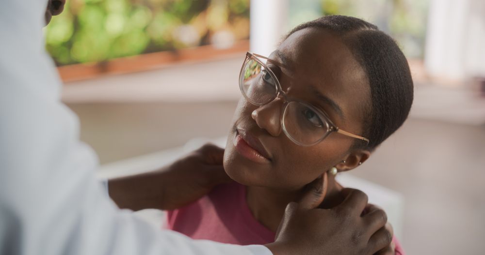 Black Physician Inspect Neck Muscles For Any Damages of a Female Patient