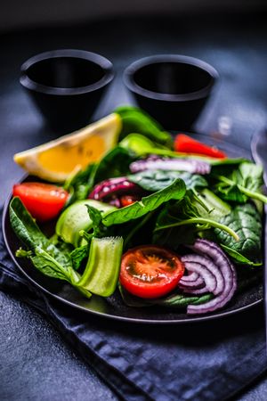 Spinach salad with cherry tomatoes, red onions and lemon slice