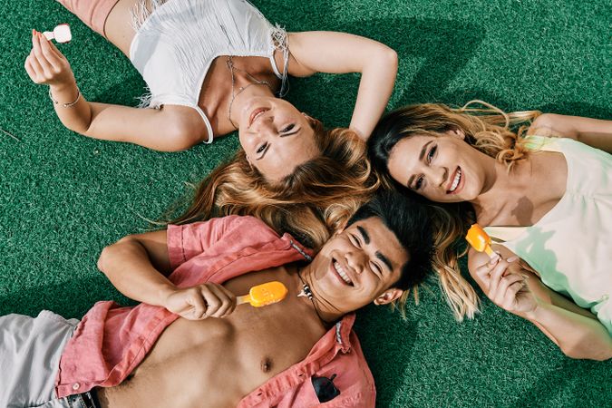 a group of young people having a good time and eating ice-cream lying on grass