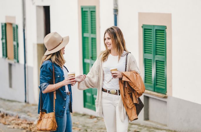 Women walking and chatting with cups of coffee