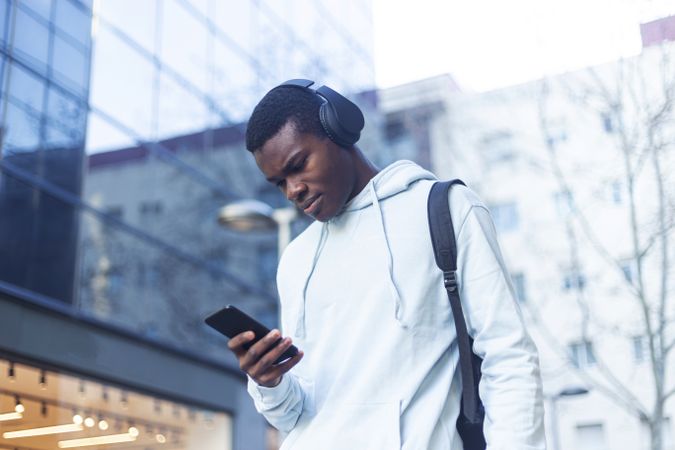 Young man standing in the street while listening music on headphones