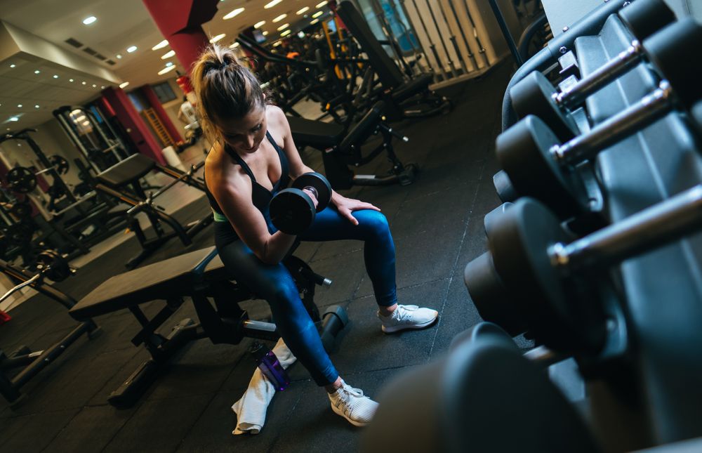 Woman lifting dumbbells on bench