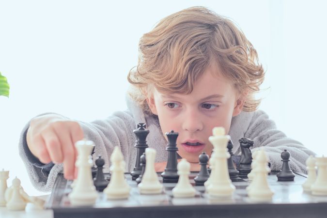 Serious preteen boy planning performing check during chess game