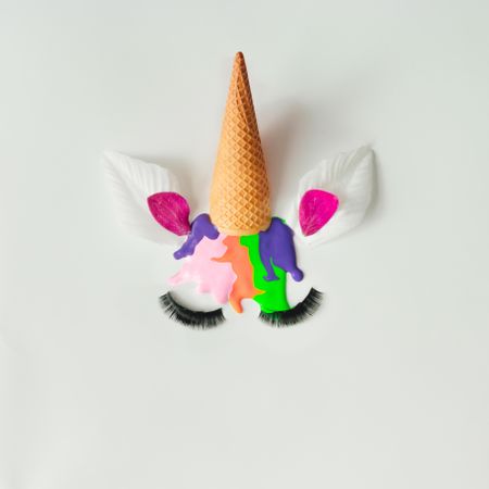 Unicorn head with flower petals and colorful ice cream melting on light background