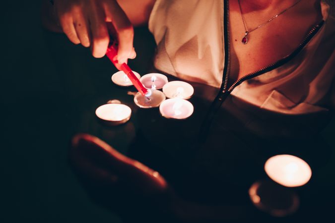 Crop person lighting candles in pool