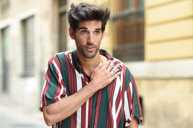 Portrait of dark haired man standing outside with hand on chest