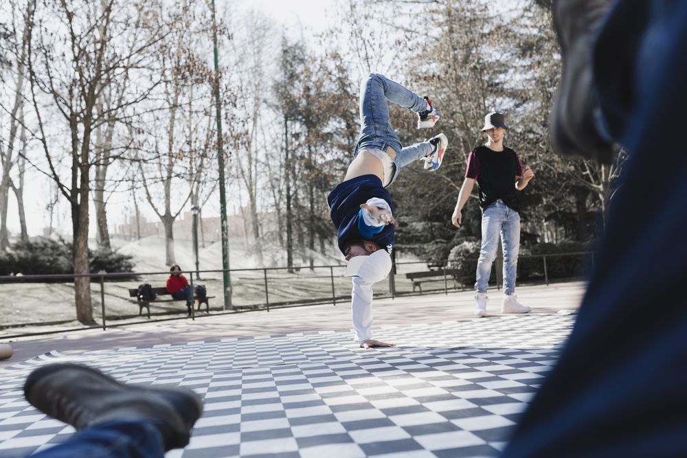 Guy looking at man dancing break dance in park