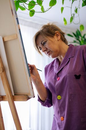 Adult woman painting canvas at home
