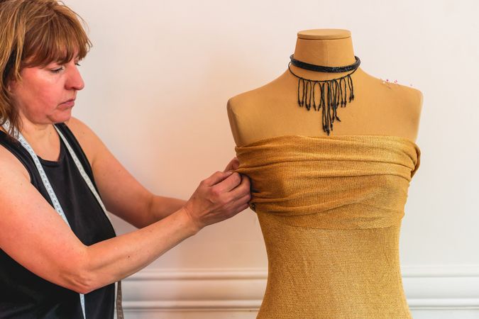 Fashion designer putting pins into fabric on mannequin