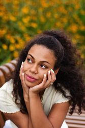 Portrait of Black female looking to the side on bench in front of flowers