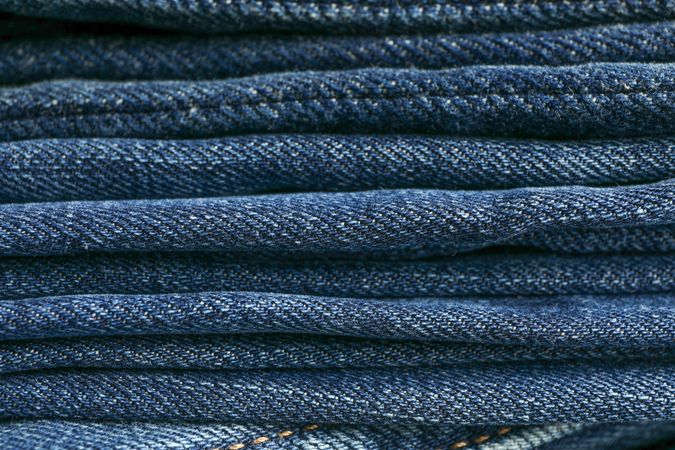 Stack of blue jeans as background, space for text