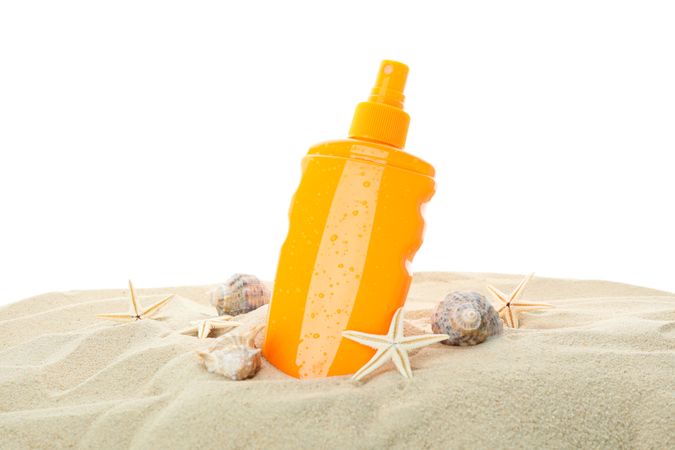 Sunscreen with starfish and seashells on clear sea sand isolated on neutral background. Summer vacation