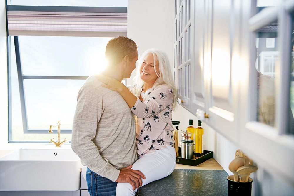 Older couple in kitchen with woman sitting on counter