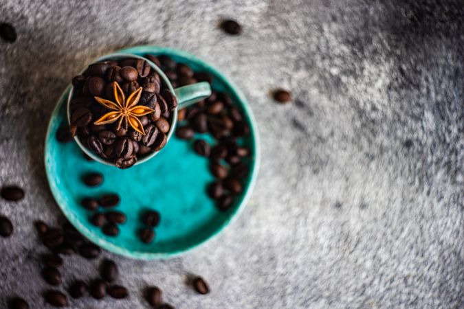 Top view of coffee beans in teal cup with star anise