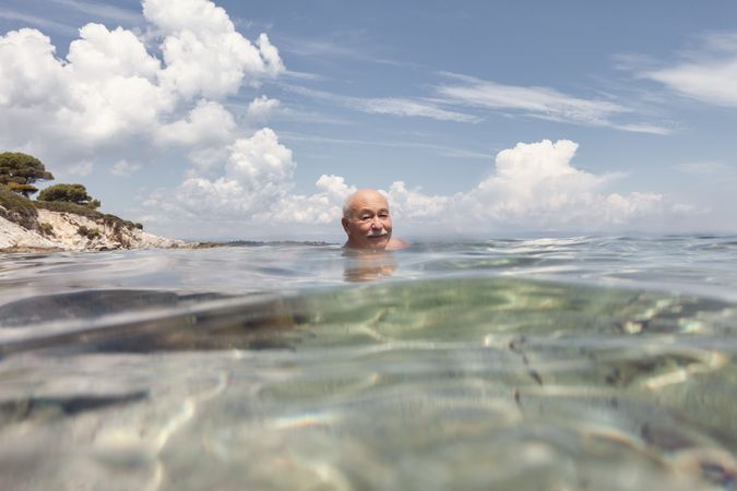 Cheerful older man swimming in sea water