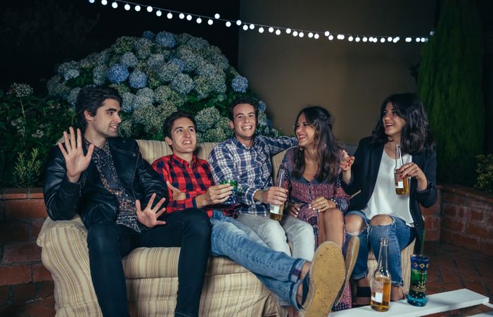 Friends sitting on a sofa ad chatting with drinks