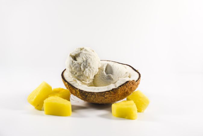 Coconut shell with scoop of ice cream and pineapple fruit chunks