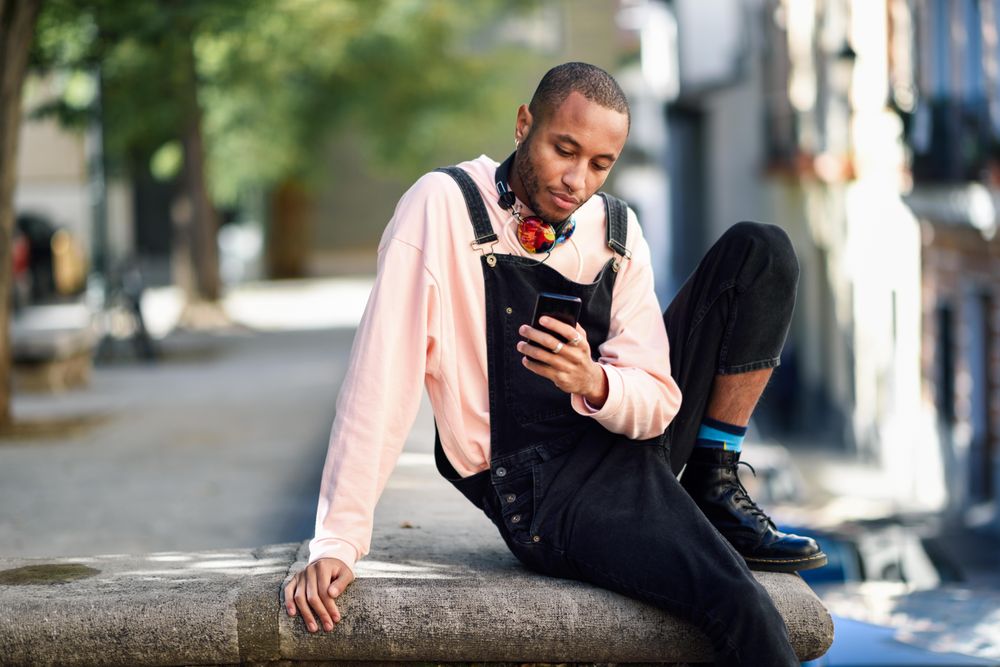 Calm male sitting in city checking phone