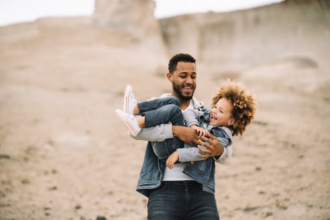 Black father playing with child on ground