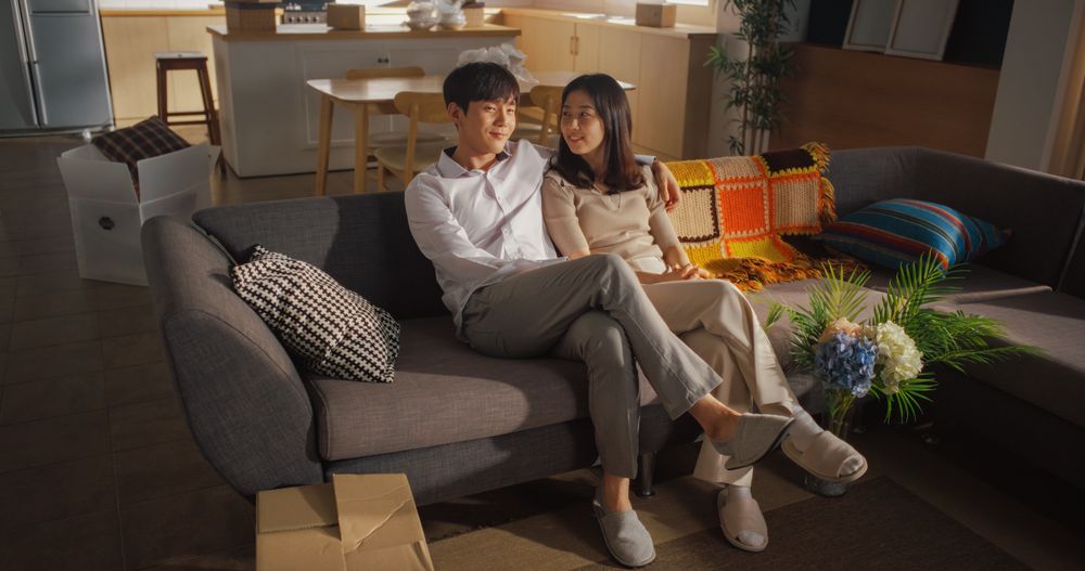 Family Home Moving in: Happy Young Korean Couple Sitting in Newly Purchased Apartment.