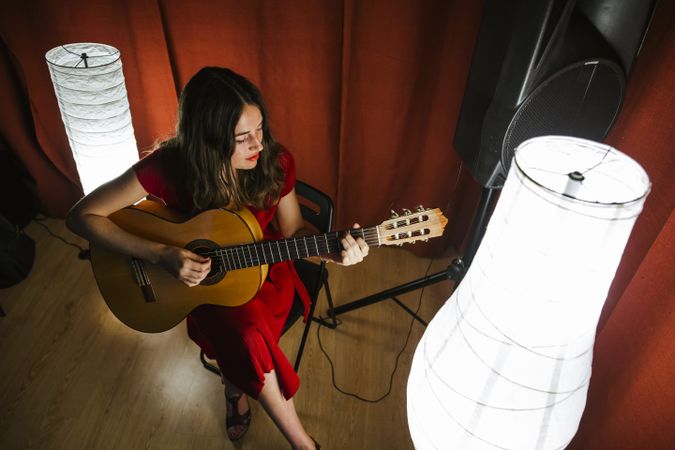 Woman singing and playing guitar on stage in lamplight