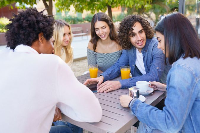 Multi-ethnic group of friends having coffee and juice outside and chatting