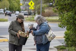 Grandmother, mother and baby with bucket of fresh floral bouquets on street