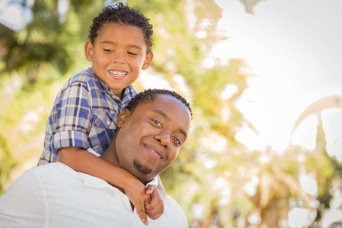 Black Father and Son Playing Piggyback Outdoors On Sunny Day