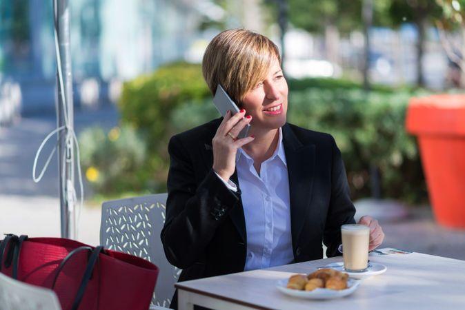 Female having snack on table outside talking on phone