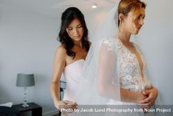 Bridesmaid helping bride to put on a veil 4Be2x5