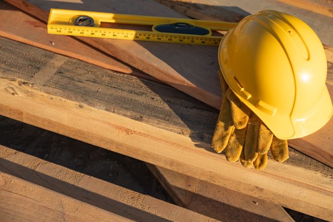 Abstract of Constrcution Hard Hat, Gloves and Level Resting on Wood Planks