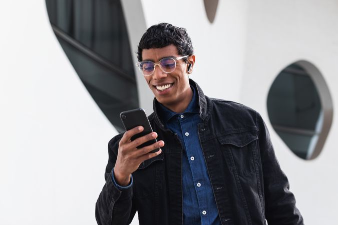 Stylish happy hispanic man with smartphone on street