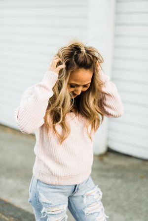 Woman in pink sweater flipping her hair and standing outdoor