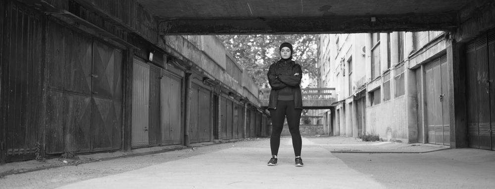 Woman with arms folded behind building