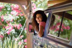 Female in pink t-shirt looking back from driver’s seat in vehicle