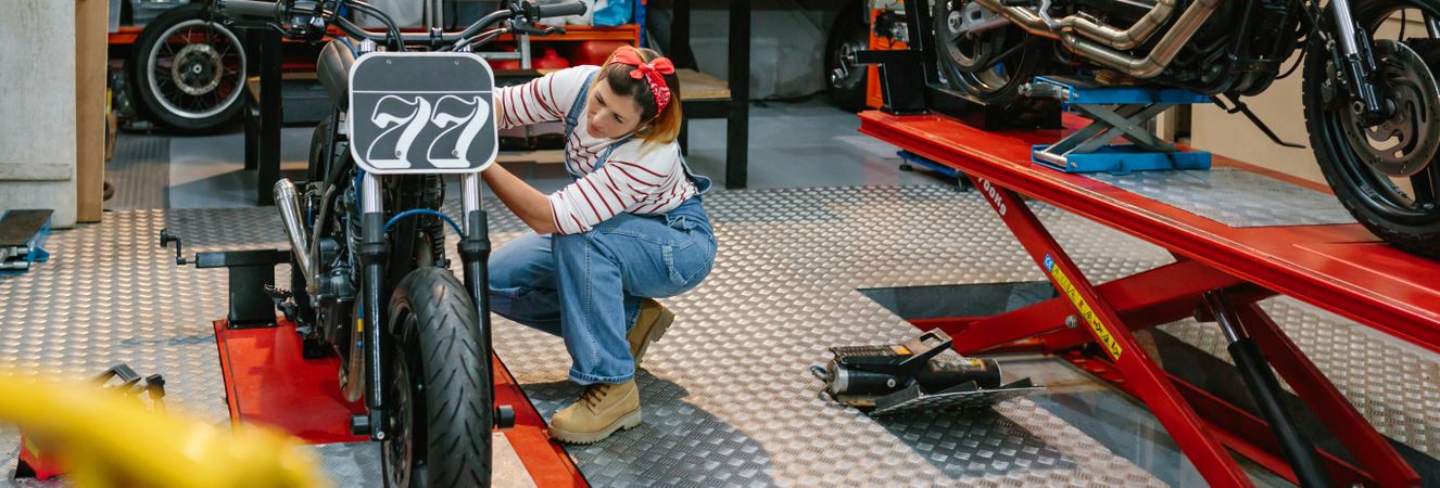 Mechanic woman checking custom motorcycle on factory