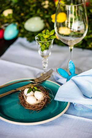 Spring table setting with bird's nest on teal plate next to glassware