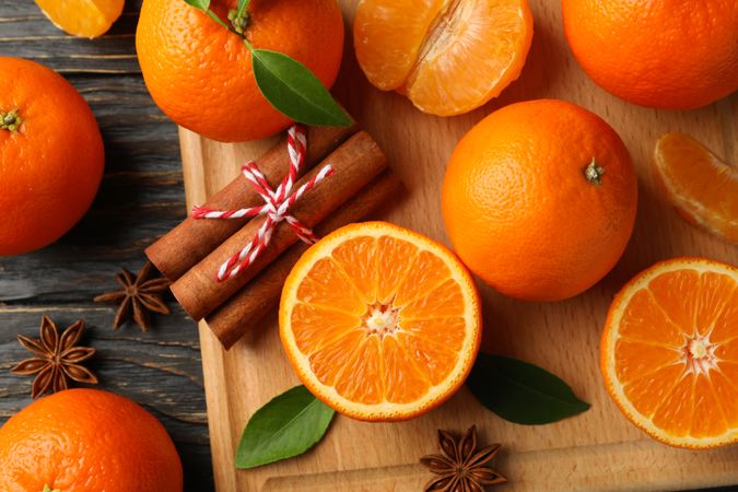 Board with mandarins and cinnamon on wooden background