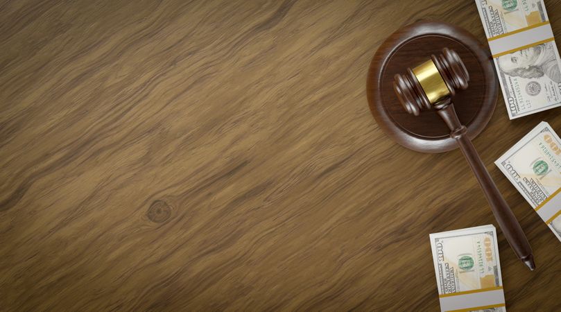 Overhead of Gavel Resting on a Table and Stacks of Thousands of Dollars with Room For Text.