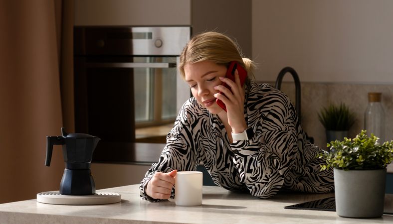 Woman talking on phone, enjoying coffee.