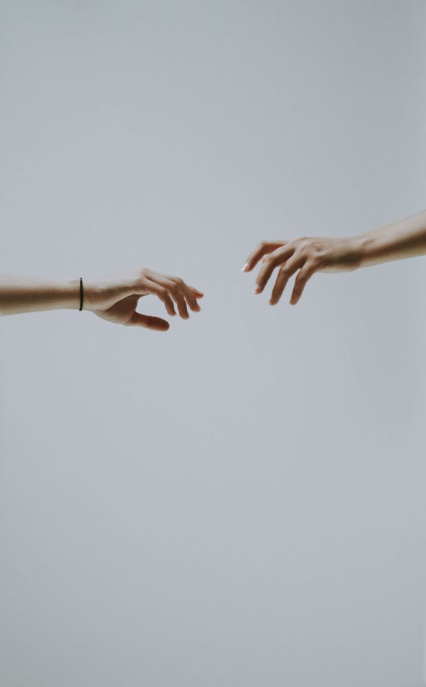 Two hands about to touch against light background