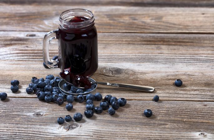 Fresh blueberry jam and berries with glass jar on rustic table