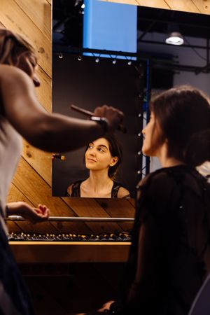Makeup artist doing makeup for young female artist